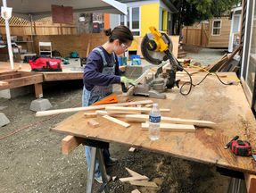 Volunteer using the chop saw at the developing T.C. Spirit village in the Central District